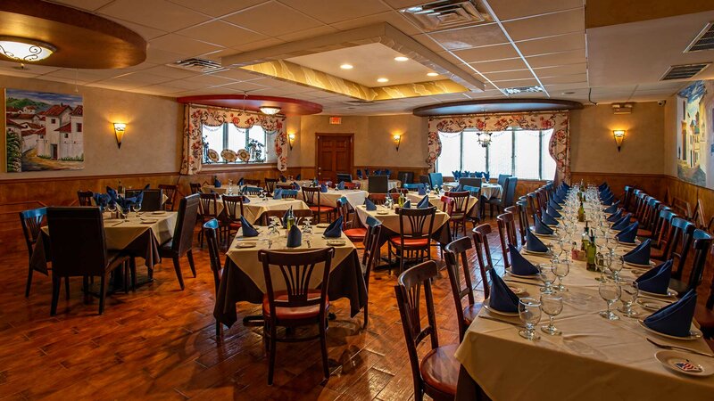 Dining room with many set tables with white table clothes and blue napkins